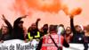 Докеры маршируют с дымовыми шашками и держат знамя во время демонстрации протеста против капитального ремонта пенсионных систем в Марселе, на юге Франции, 5 декабря