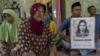Члены семьи обезглавленной индонезийской горничной Сити Зайнаб держат плакат (R) с ее портретом в их семейном доме в Бангкалане, провинция Восточная Ява, 15 апреля 2015 года