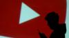 силуэт мобильного пользователя виден рядом с проекцией на экран логотипа YouTube на этой иллюстрации, сделанной 28 марта 2018 г.
