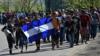 Мигранты из Гондураса идут с национальным флагом Гондураса, направляясь в Пуэрто-Барриос, в департаменте Изабаль, Гватемала