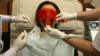 Женщина проходит процедуру отбеливания зубов