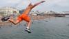 Мальчик прыгает в море, наслаждаясь жаркой погодой на Брайтон-Бич