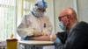 Медсестра в защитных костюмах берет кровь на анализ на антитела к COVID-19 в одной из поликлиник Москвы