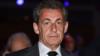 Николя Саркози, одетый в темный костюм и галстук ночью, смотрит прямо в камеру на этой фотографии крупным планом 2018 г.