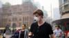 Мужчина носит маску, чтобы защитить себя от дыма во время прогулки по центру Сиднея во вторник