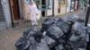 Женщина в Alum Rock проходит мимо мешков для мусора