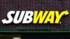 На этом снимке крупным планом виден логотип цепочки бутербродов Subway, прикрепленный к кирпичной стене