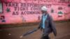 Мужчина в маске в качестве меры предосторожности проходит мимо стены с предупредительными граффити во время пандемии коронавируса.