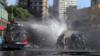 Водомёт полиции по охране общественного порядка обливает водой демонстрантов во время акции протеста в Сантьяго.