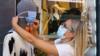 Женщина надевает маску на манекен возле магазина одежды в Аранда-де-Дуэро, недалеко от Бургоса, 7 августа