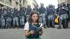 Ольга Мисик читает конституцию, за ее спиной стоят десятки омоновцев