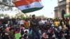 Протестующие и студенты выкрикивают лозунги и держат индийские флаги, протестуя против жестоких столкновений
