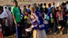 Эфиопская женщина, бежавшая от войны в северном регионе Тыграй, несет свой продовольственный паек, пока другие выстраиваются в очередь в лагере Ум-Ракоба на границе Судана и Эфиопии, Судан, 19 ноября 2020 г.