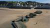 На этом виде с воздуха понтоны из временной гавани Малберри, построенной союзниками во время Второй мировой войны, построенной во время вторжения в День Д, лежат на пляже 30 апреля 2019 года в Арроманш-ле-Бен,