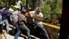 Фермеры держат деревянный сундук, пытаясь открыть дверь, чтобы войти в плотину Ла Бокилья во время акции протеста