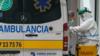 Медицинский работник в защитном костюме помогает мужчине выйти из машины скорой помощи возле больницы Бургоса на севере Испании 23 марта 2020 г.