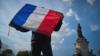 Протестующий машет французским трехцветным флагом с надписью «Свобода слова» во время антитеррористической акции в воскресенье