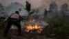 Сотрудник полиции пытается тушить пожар в Индонезии
