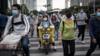 Жители носят маски, катаясь на велосипедах 11 мая 2020 года в Ухане, Китай.