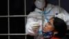 Медицинский работник берет образец мазка у женщины в Дели