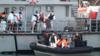 Группа людей, которых считают мигрантами, высаживаются с палубы HMC Seeker, когда они поднимаются на борт пограничного отряда в гавани Дувра
