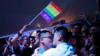 Гей-пара целуется во время вечеринки в круизе в открытом море по пути в Сасебо, Япония, 15 июня 2017 года. Над ними висит флаг гордости.