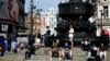 Люди сидят на ступенях площади Пикадилли, страдая от коронавирусной болезни
