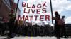 Протестующие держат плакат Black Lives Matter на протесте в Бруклине