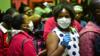Путешественники, носящие маски в качестве защитной меры, ждут проверки температуры на пограничном посту с Кенией в Наманге