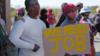 Протестующие выставляют плакат возле горнопромышленного поселения Сераленг 18 мая 2020 года в Рустенбурге, Южная Африка.
