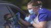 Медицинский работник берет мазок у автомобилиста в центре тестирования