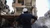 Член сирийских добровольцев гражданской обороны, известный как «белые каски», смотрит на разрушенное здание после сообщения о воздушном ударе по удерживаемому повстанцами городку Дума на восточной окраине столицы Дамаска