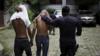 Подозреваемых членов банды 18-й улицы охраняет полицейский в Сан-Сальвадоре 29 июля 2015 года.