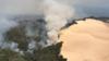 Облако дыма поднимается из леса рядом с песчаными дюнами на острове Фрейзер во время лесных пожаров в начале декабря 2020 года