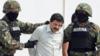 Мексиканского наркоторговца Хоакина Гусмана Лоэра сопровождают морские пехотинцы, когда он представлен прессе 22 февраля 2014 года в Мехико.