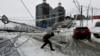 Мужчина идет под поврежденным столбом, покрытым льдом после ледяного дождя в дальневосточном городе Владивосток, Россия