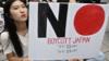 Протестующие из Южной Кореи держат табличку с надписью «Бойкотируйте Японию» в Сеуле