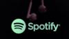 Пара наушников свисает с верхней части рамки перед логотипом Spotify