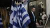 Мужчина проходит мимо прилавка с греческими флагами