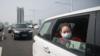 Девушка сидит в машине, когда движение останавливается во время молчания памяти погибших от коронавируса в Ухане.