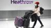 Женщина толкает багаж через аэропорт Хитроу