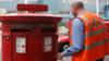 Почтовый работник опорожняет почтовый ящик в центре Лондона,