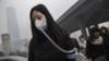 Женщина в маске и фильтре идет во время сильного загрязнения в Пекине, Китай