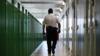 Тюремный офицер проходит мимо дверей камеры в HMP Berwyn, Wrexham
