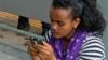 Женщина смотрит в свой телефон в Эфиопии