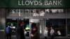 Люди стоят на улице или проходят мимо отделения банка Lloyds