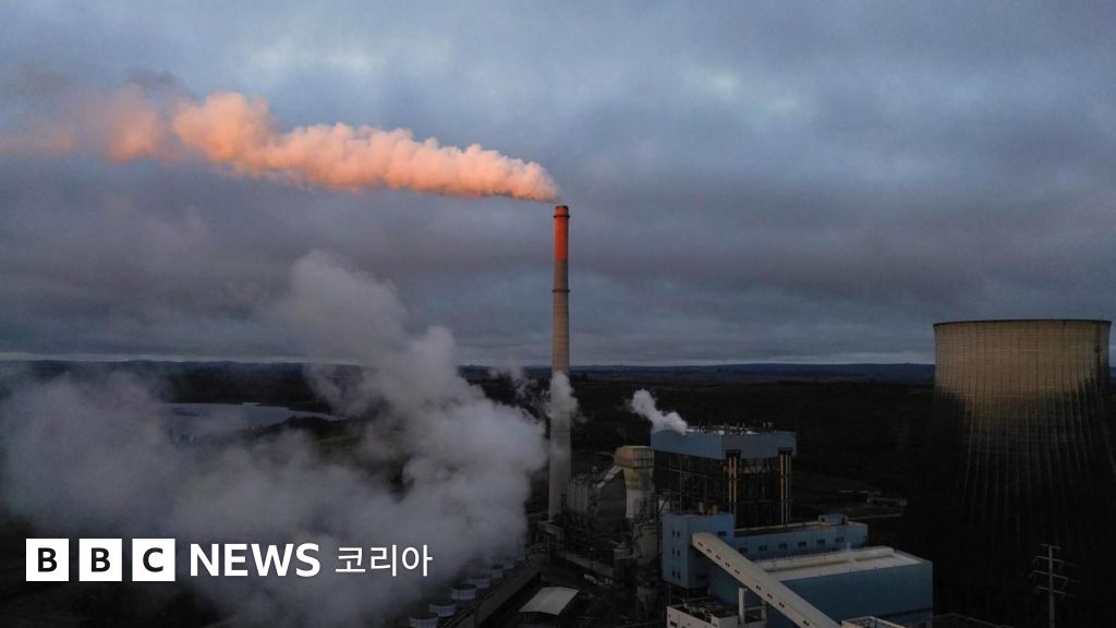 석탄 화력 발전소의 전경. 높은 굴뚝 꼭대기에서 가스가 하얀 구름처럼 빠져나오고 있다.