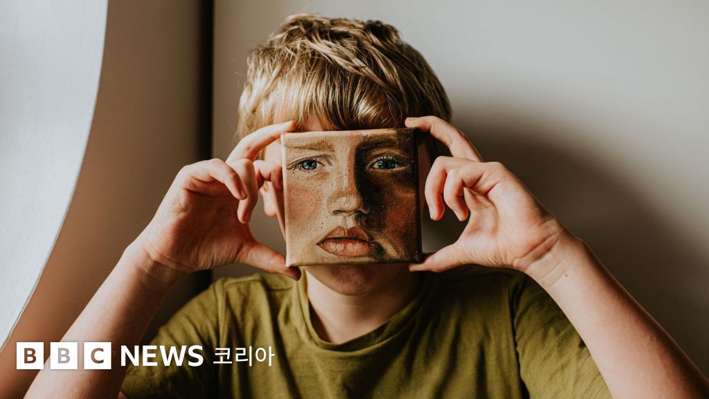 작은 얼굴 그림을 들고 있는 소년