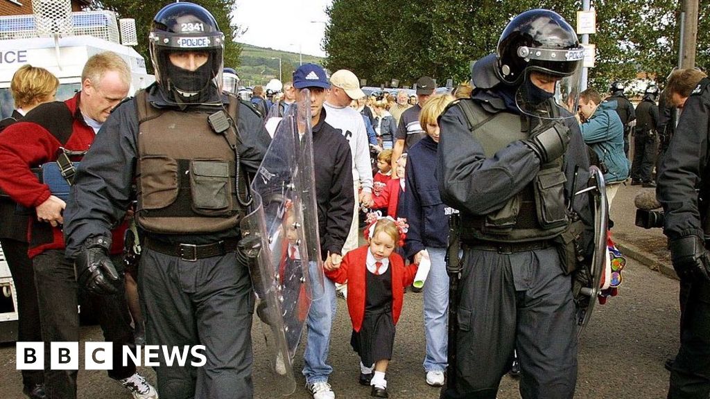 Police officers in riot gear escorted schoolgirls and their families past the protesters