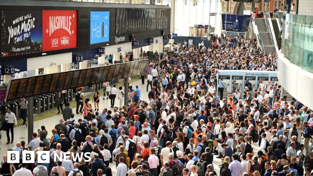 Commuters wait on a railway platform